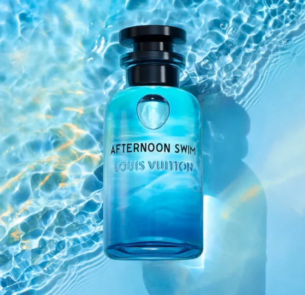 Flakon perfum Louis Vuitton Afternoon Swim w odcieniach błękitu i turkusu, częściowo zanurzony w wodzie z widocznymi falami i refleksami światła, z nazwą i czarnym korkiem.