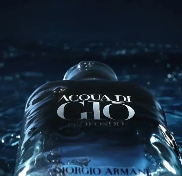 Ciemnogranatowy flakon perfum Giorgio Armani Acqua di Gio Profondo częściowo zanurzony w wodzie, z widocznymi falami i refleksami światła, oraz częścią napisu ACQUA DI GIO na butelce.