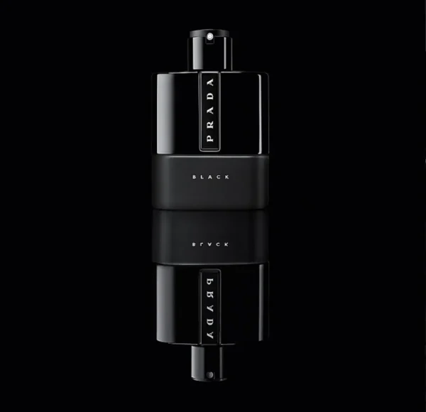 Czarny flakon perfum Prada Luna Rossa Black, z błyszczącą górną częścią i matowym dołem, z widocznym napisem PRADA i BLACK, stojący na lustrzanej powierzchni na czarnym tle.