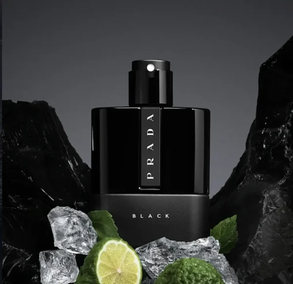 Czarny flakon perfum Prada Luna Rossa Black, stojący na tle ciemnych kamieni, otoczony przez limonki, lód i liście mięty.