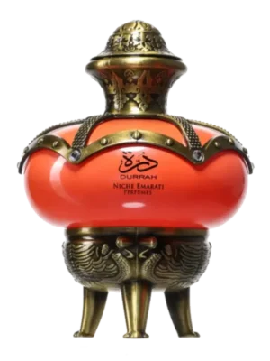 Flakon perfum Lattafa Niche Emarati Durrah, o kulistym kształcie w kolorze pomarańczowym, z ozdobnym, metalowym stojakiem i opaską w kolorze starego złota, z ornamentowym korkiem.