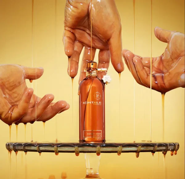 Flakon perfum Montale Honey Aoud, stojący na szklanej tacy, z miodem spływającym z dłoni i ociekającym po butelce.