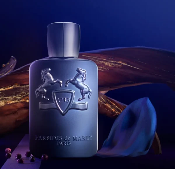 Artystyczne zdjęcie flakonu perfum Parfums de Marly Layton w tajemniczym, niebieskim oświetleniu. Matowa butelka stoi na ciemnej powierzchni w otoczeniu ziaren pieprzu i elementów dekoracyjnych, tworząc luksusową i zmysłową atmosferę.